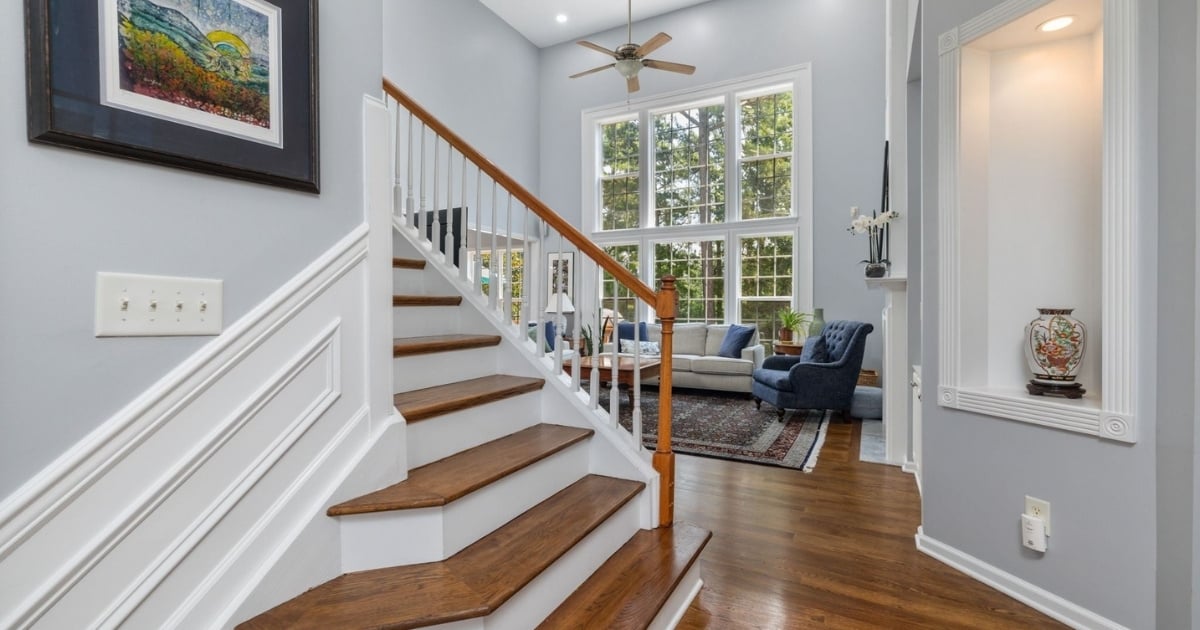Stock image of a bright foyer with hardwood staircase, tall windows, and sitting area in Northern California
