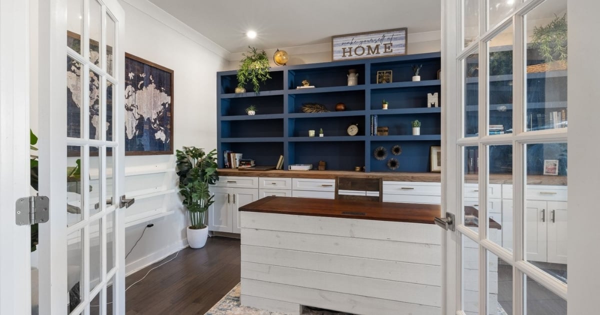 Stock image of a home office with blue built-in shelving, white cabinetry, wood desk, and French doors in Northern California