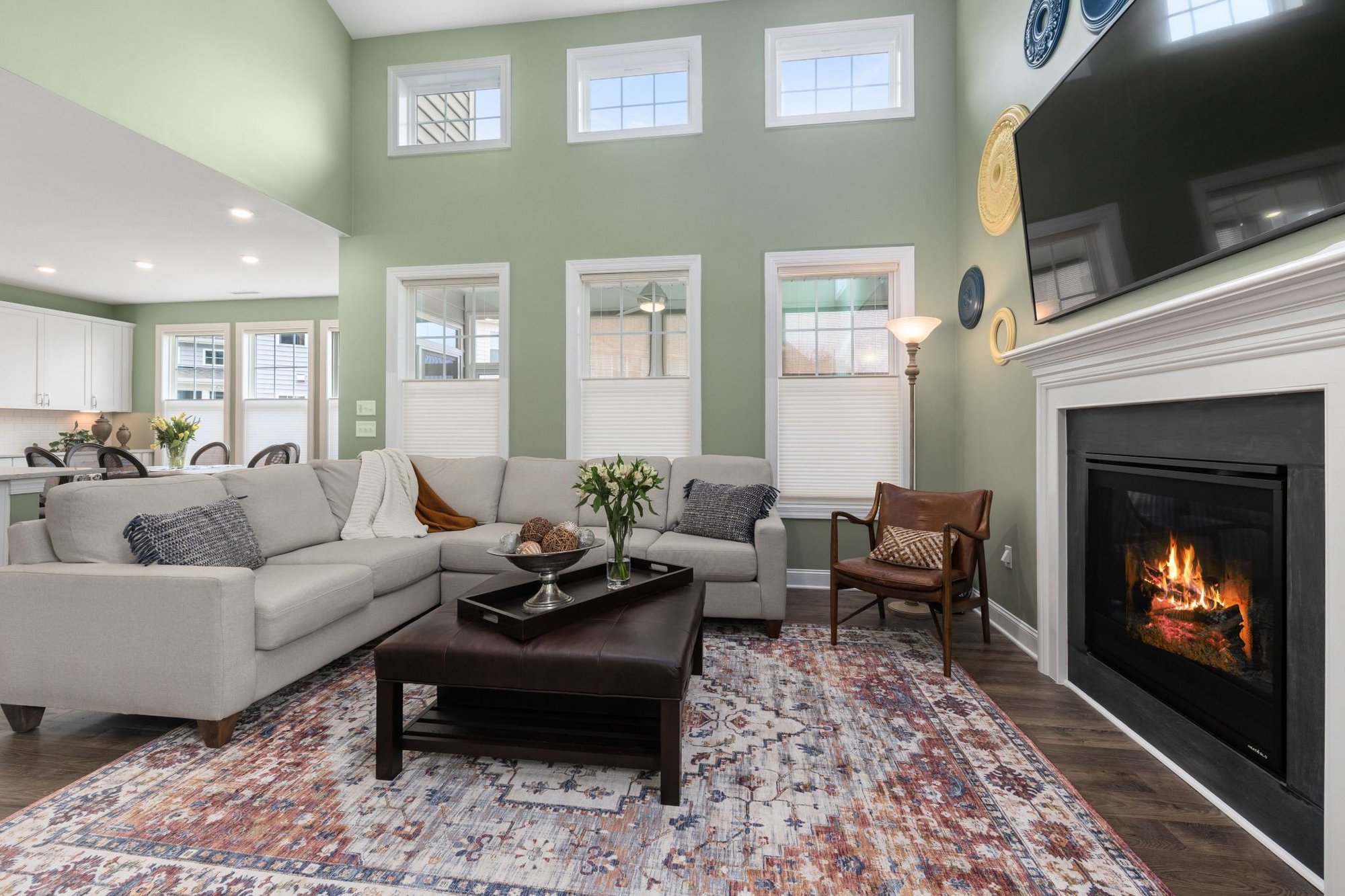 Stock image of a living room with vaulted ceiling, sectional sofa, fireplace, and large windows in Northern California -optimized