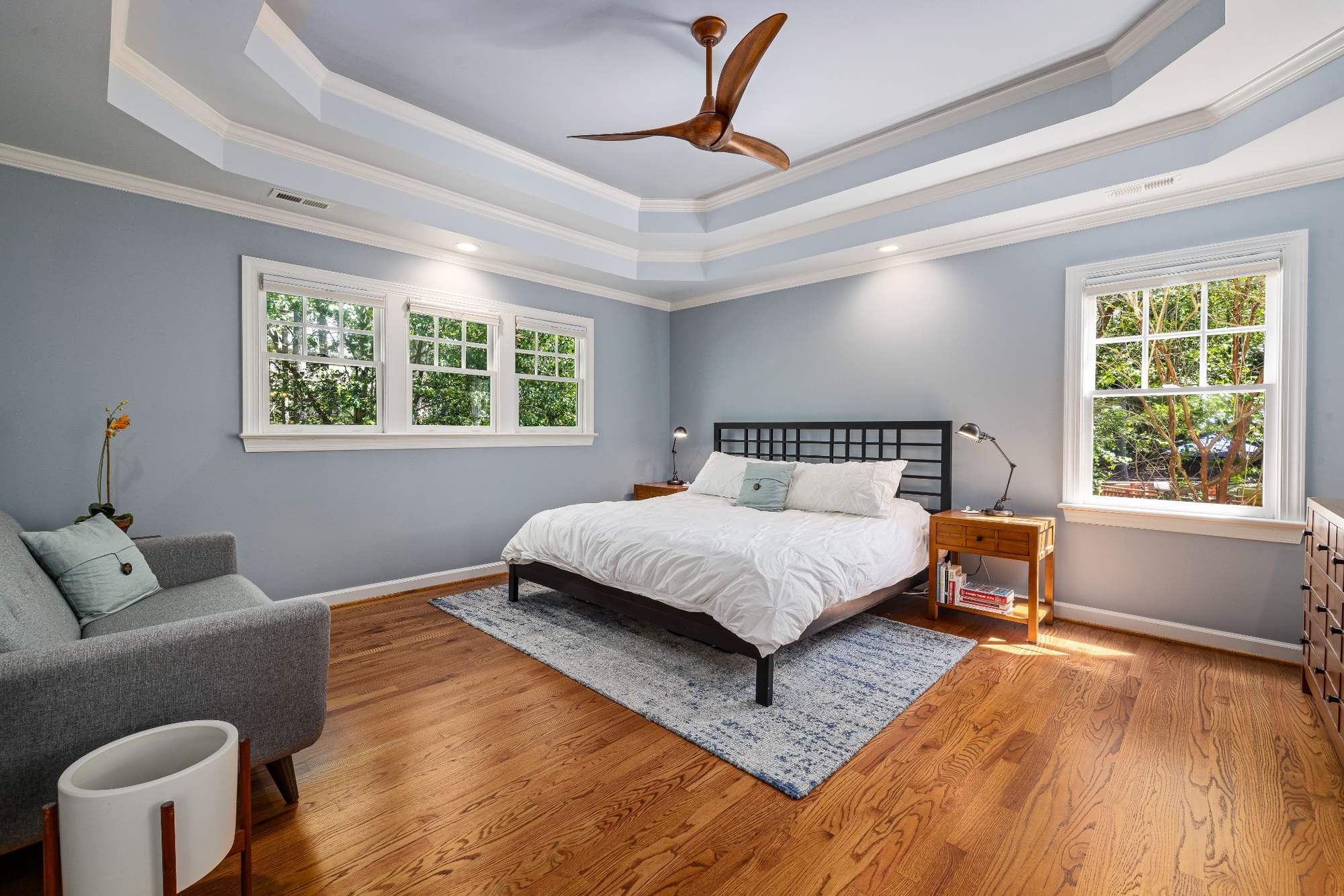 Stock image primary bedroom with hardwood floors, tray ceiling, and large windows in Northern California - optimized
