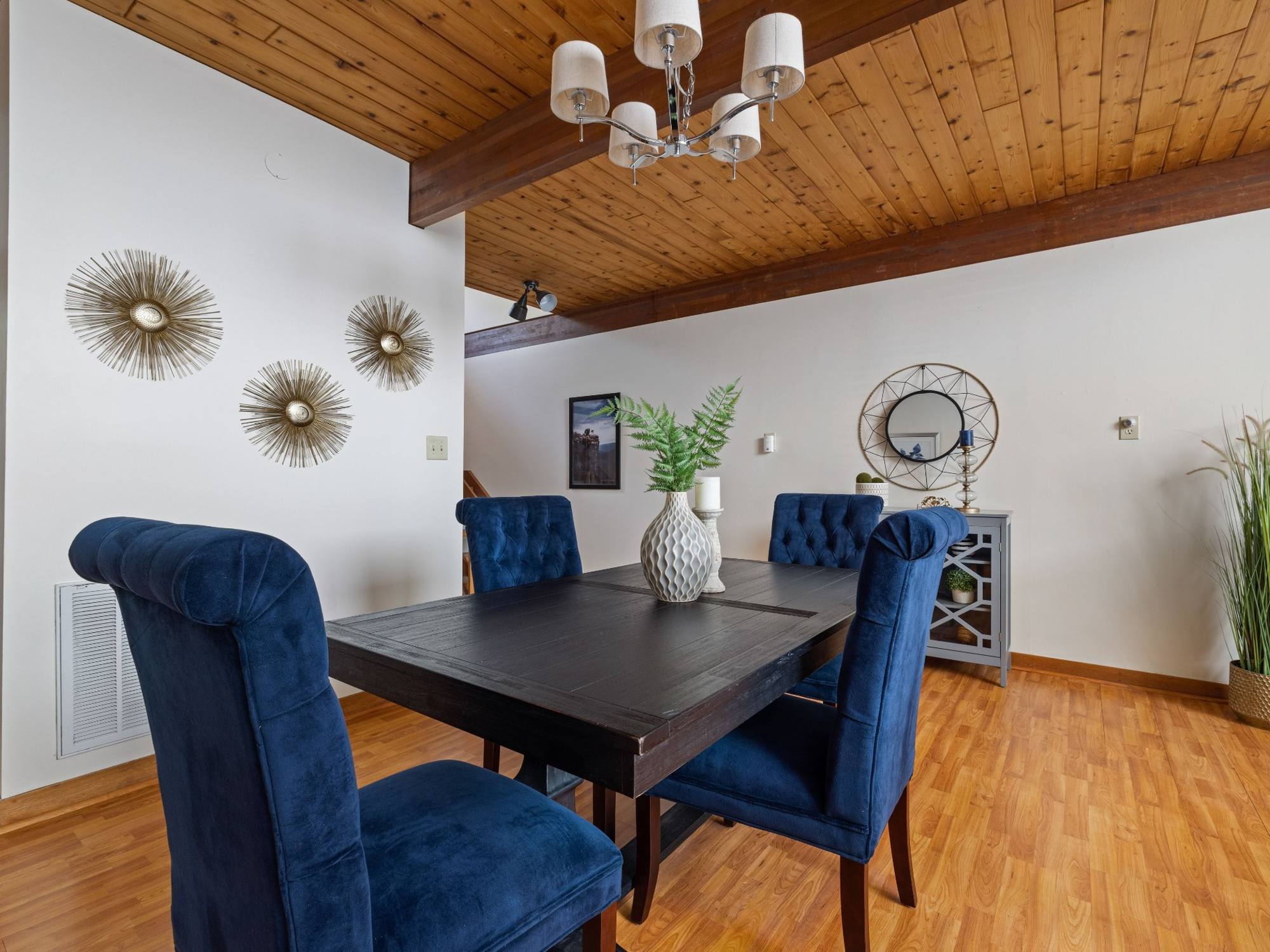 Stock image of a dining room with blue chairs, exposed wood beams, wood ceiling, and hardwood floors in Northern California - optimized