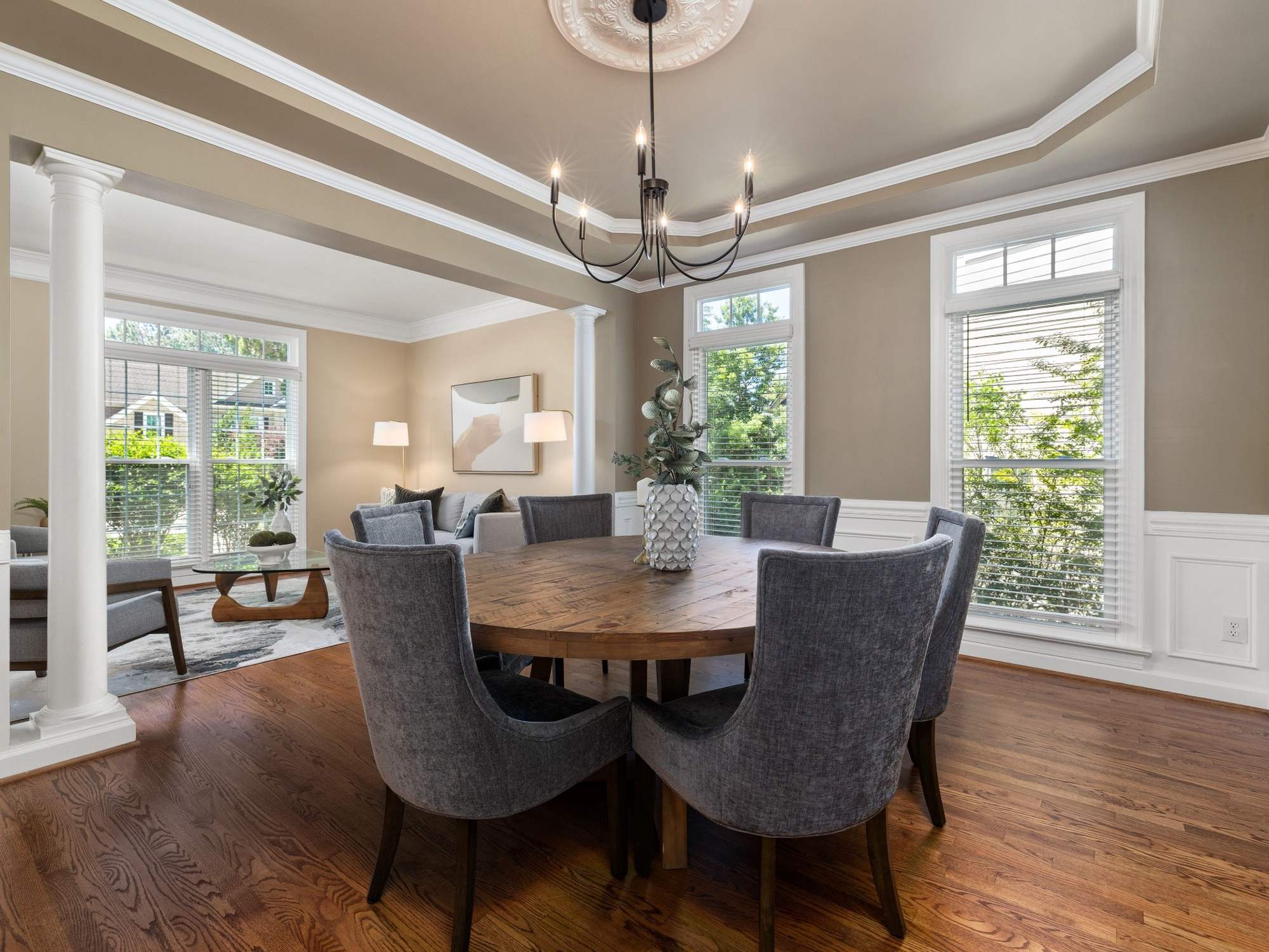 Stock image of a formal dining room with tray ceiling, hardwood floors, round table, and large windows in Northern California - optimized