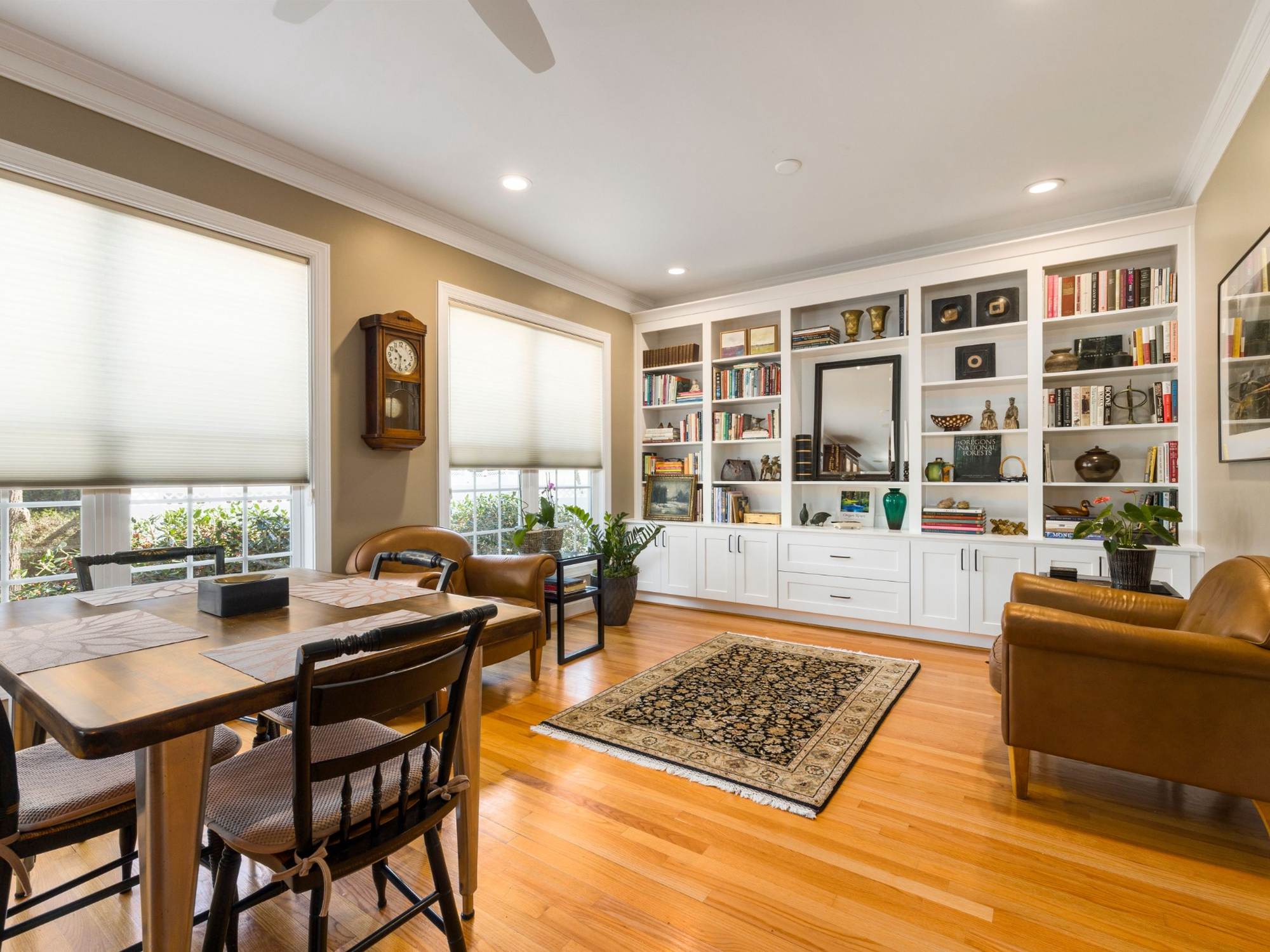 Stock image of a home office with custom white built-ins, hardwood floors, leather chairs, and large windows in Northern California - optimized