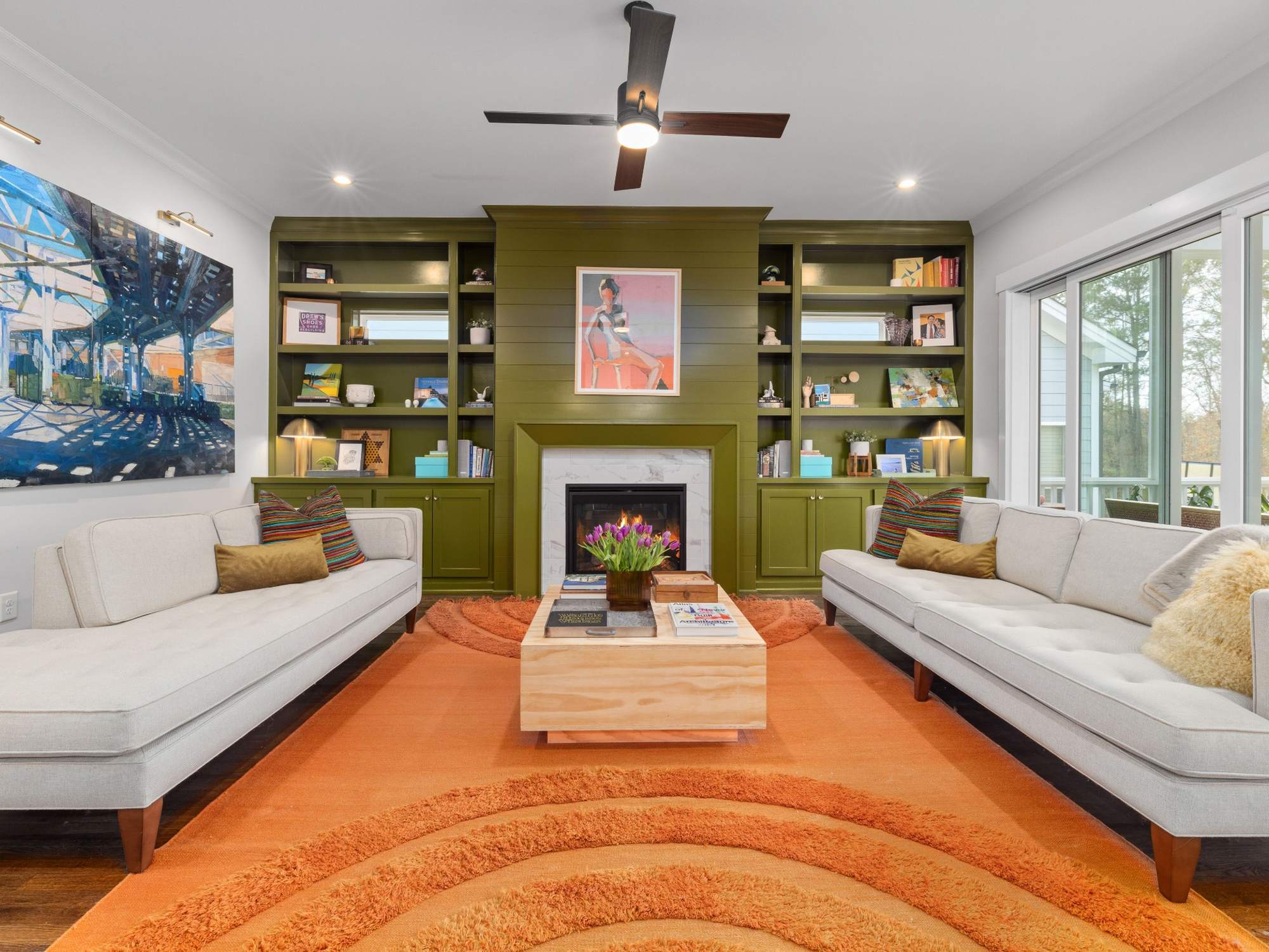 Stock image of a living room with green built-ins, fireplace, white sofas, and colorful decor in Northern California - optimized