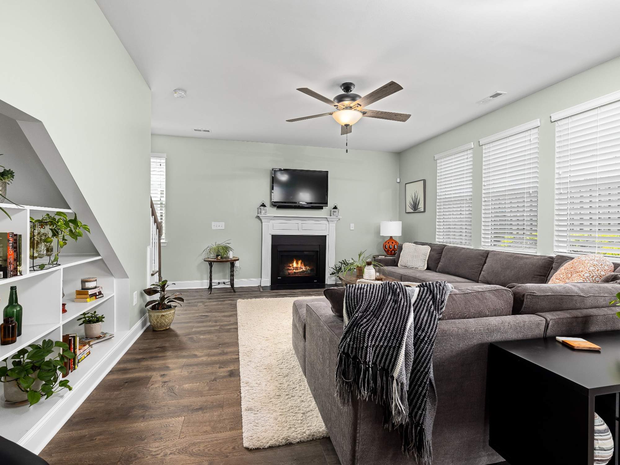 Stock image of a living room with sectional sofa, fireplace, built-in shelving, and large windows in Northern California - optimized