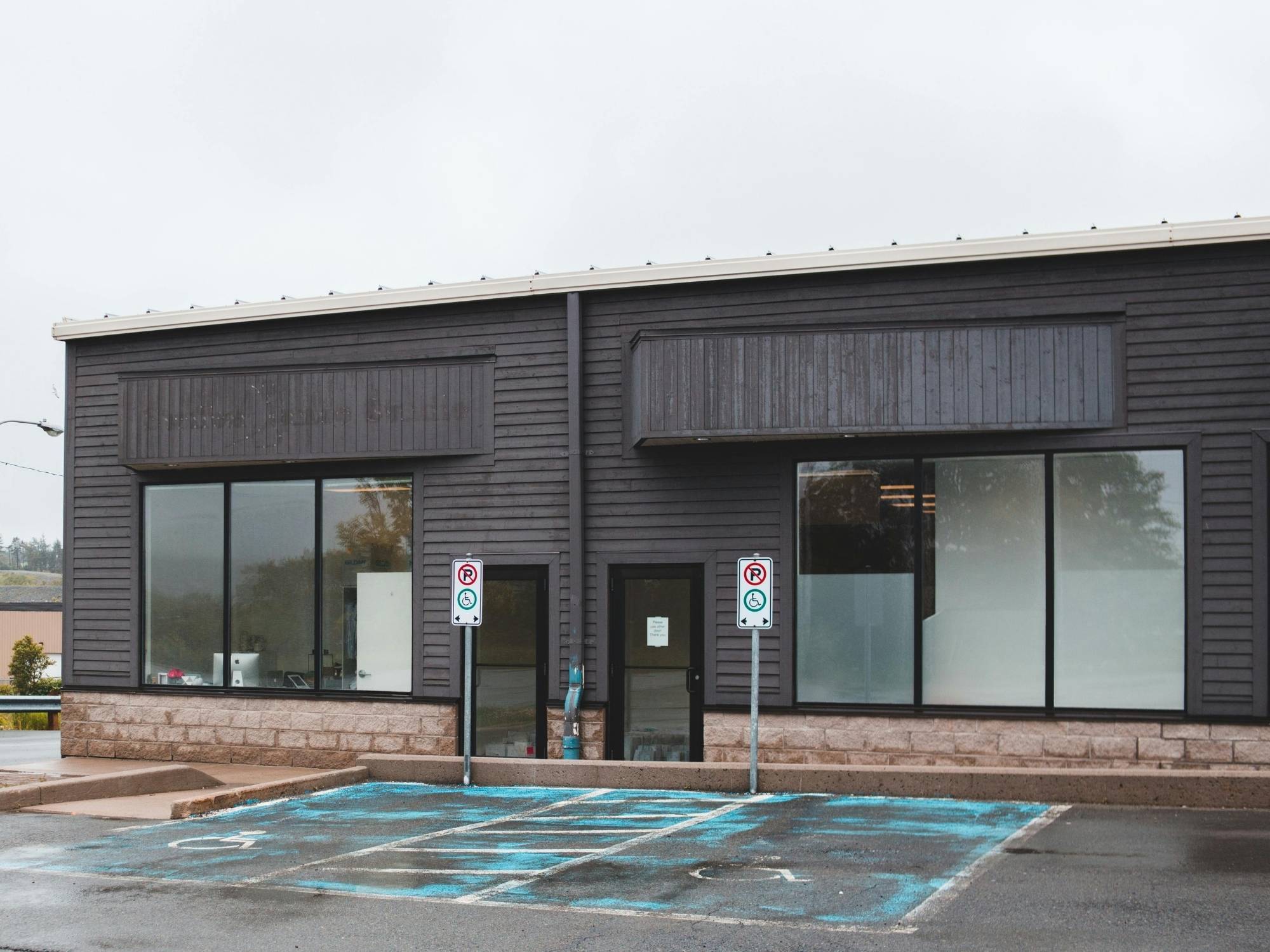 Stock image of a small commercial building with dark siding, large windows, and accessible parking in Northern California - optimized