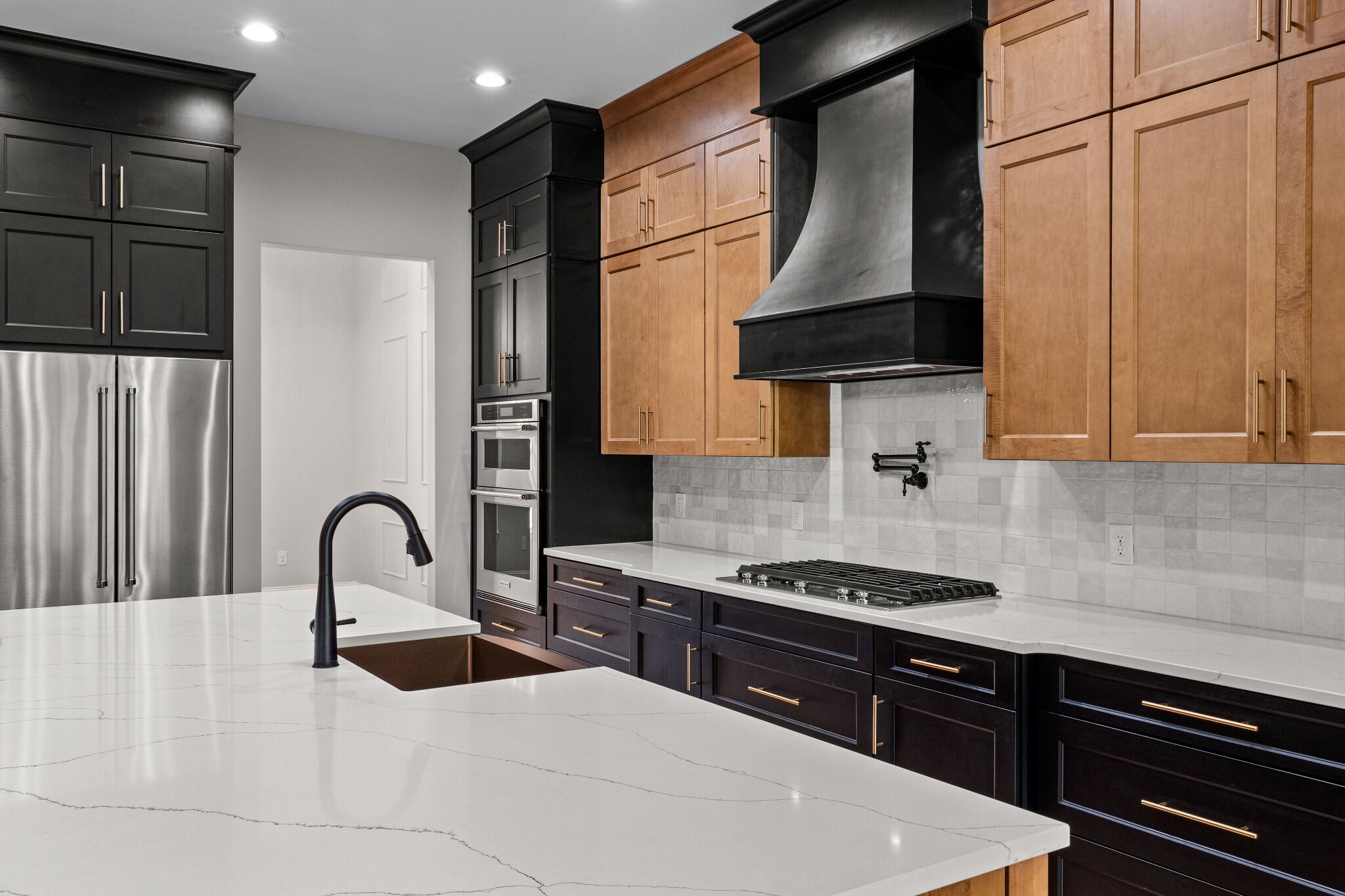 Stock image of two-tone kitchen with wood cabinets, black range hood, and quartz island northern california -optimized