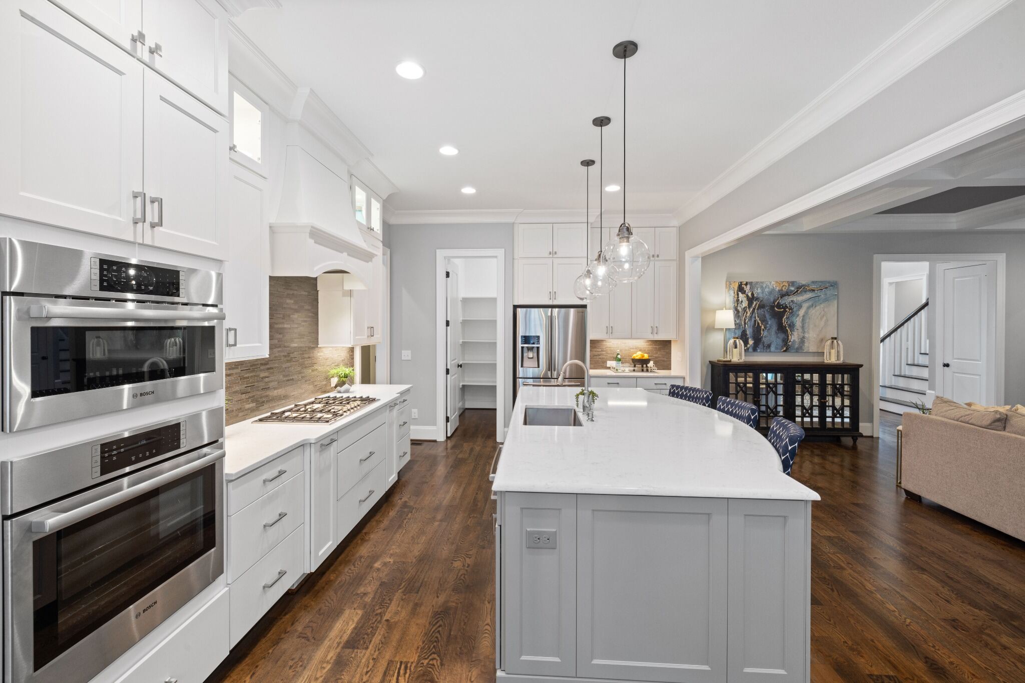Stock image of white kitchen with large island, glass pendant lights, stainless appliances, and wood floors northern california -optimized