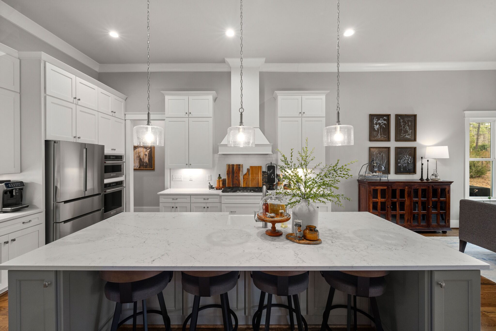 Stock image of white kitchen with large quartz island, pendant lights, and stainless appliances northern california -optimized