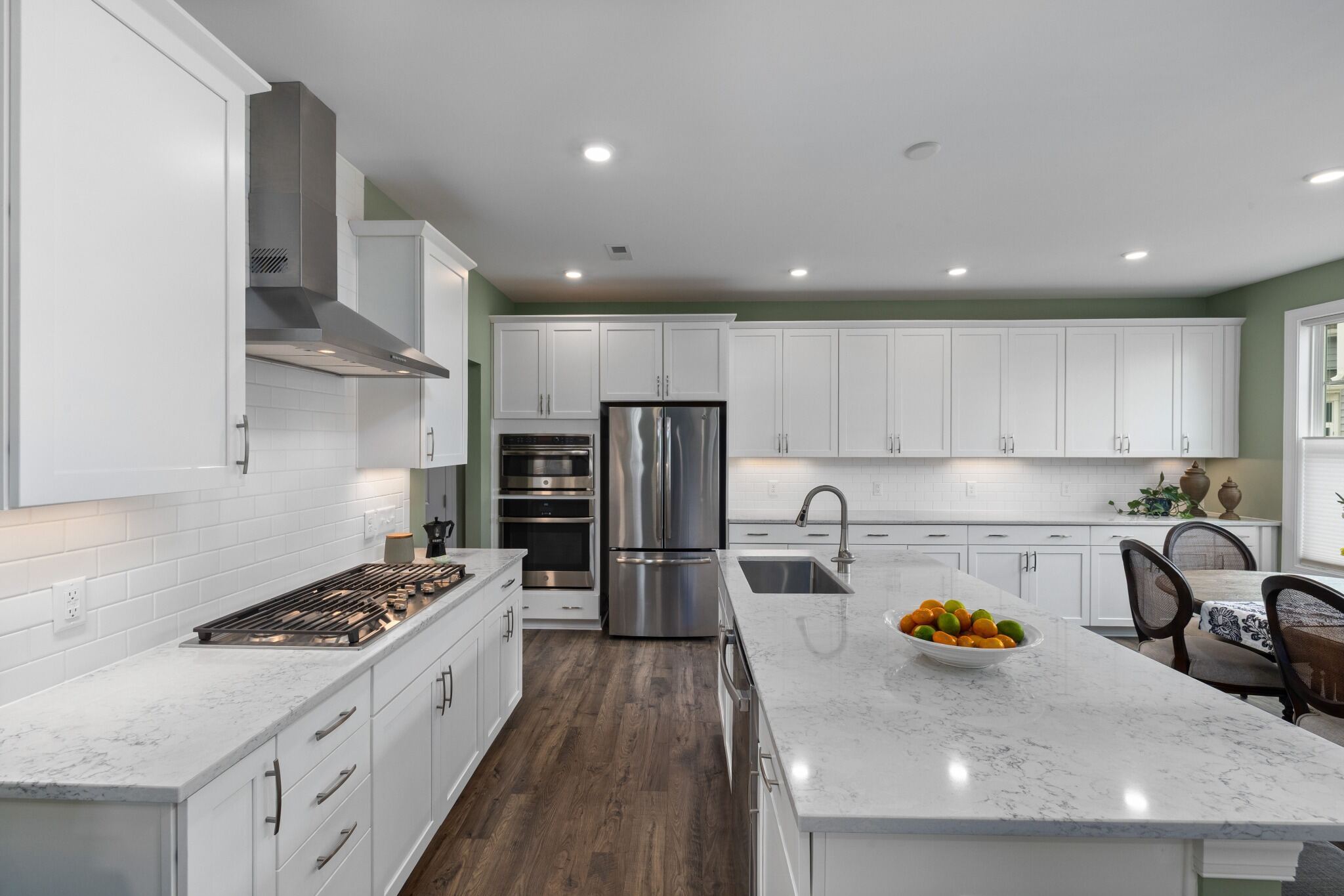 Stock image of white kitchen with quartz island, stainless appliances, and wood floors northern california -optimized