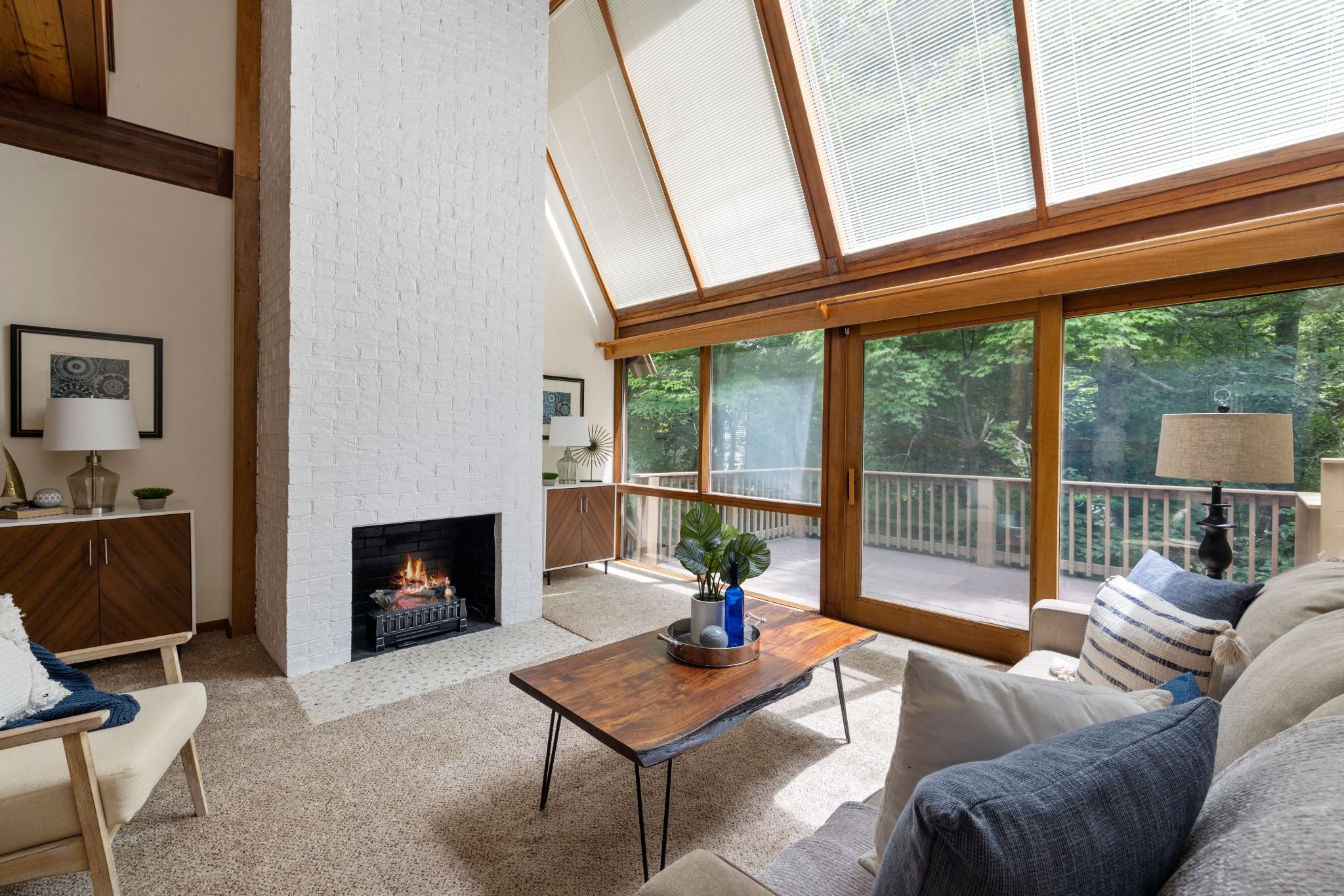 Stock image of a cozy living room with white brick fireplace, wood accents, and large windows in Northern California -optimized