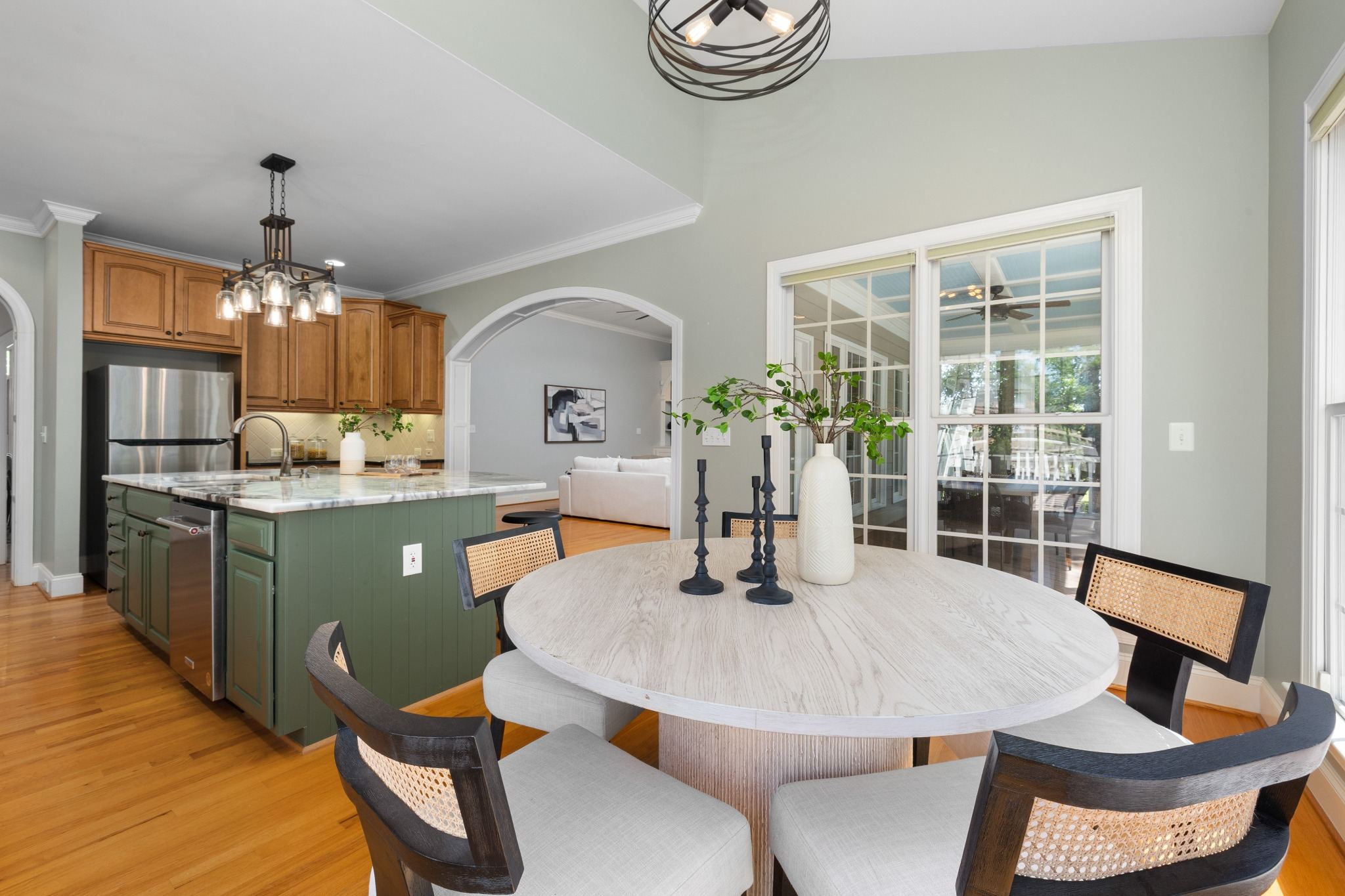 Stock image of a dining area beside a kitchen with green island cabinetry and wood floors in Northern California -optimized