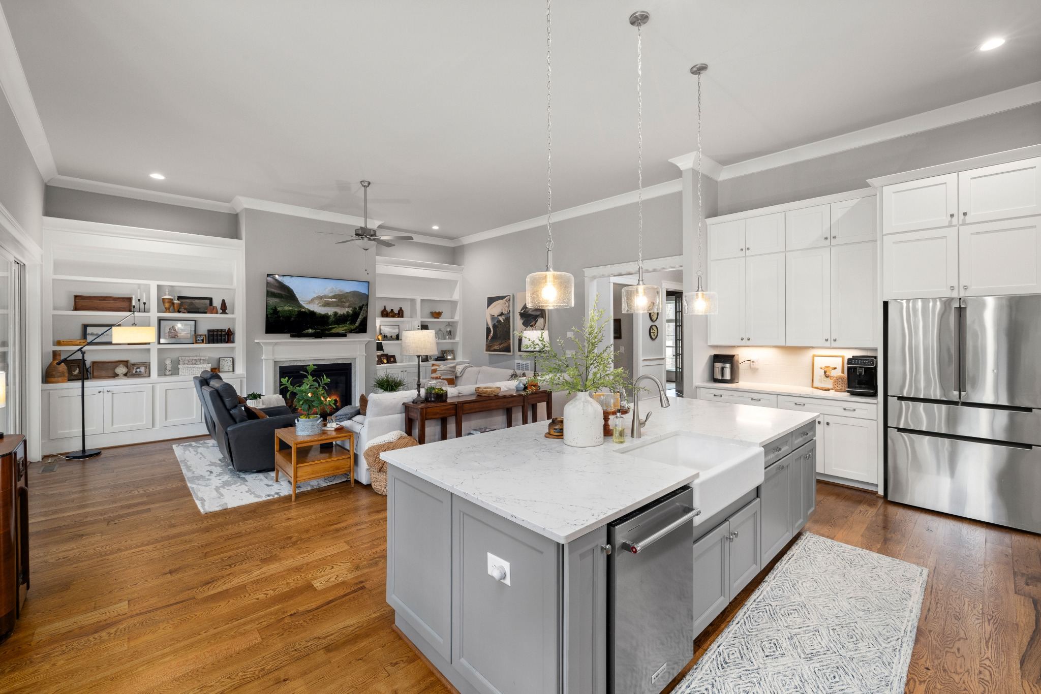 Stock image of an open kitchen and living room with large island, white cabinetry, and fireplace in Northern California -optimized